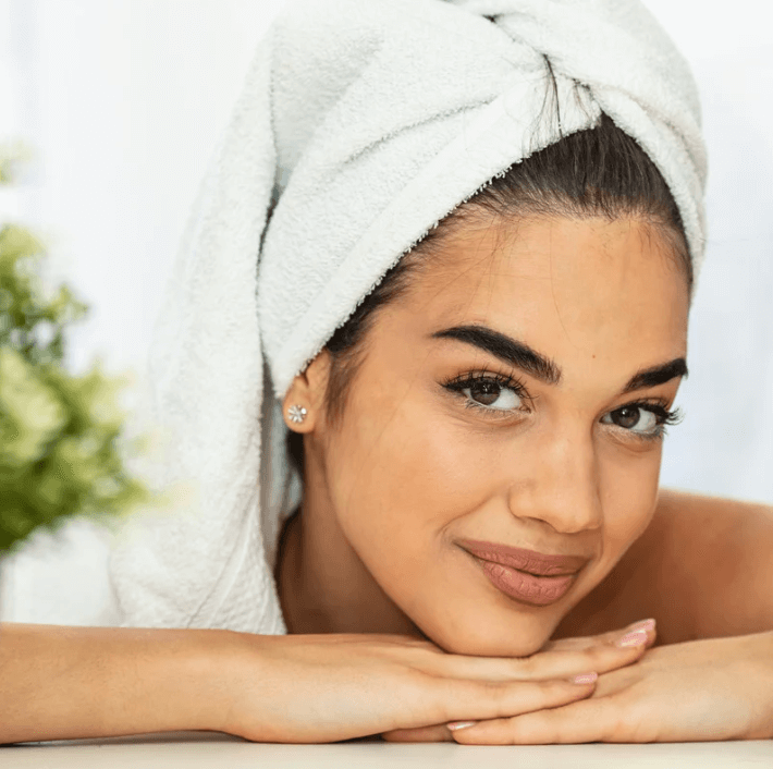 Woman with towel on head showing refreshed skin after using Luxe Honey Repairing Essence.