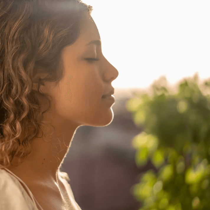 A woman enjoying a calming moment outdoors, showcasing the soothing effects of the Ultra Relief Roller.